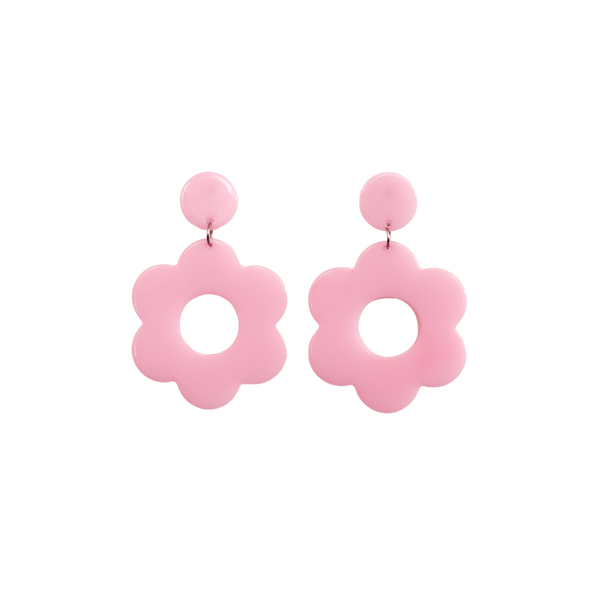 A pair of light pink bold and playful statement earrings in a retro-inspired daisy flower design. The earring has a large, light pink acrylic flower with a circular cutout center, hanging from a matching light pink circular stud. The petals are rounded, giving off a fun, 70's style far out vibe!!