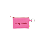 A multi functional small zippered pouch with a gold key ring. The saying "Stay Toxic" as well as the zipper is red while the main color of the pouch is bright pink.