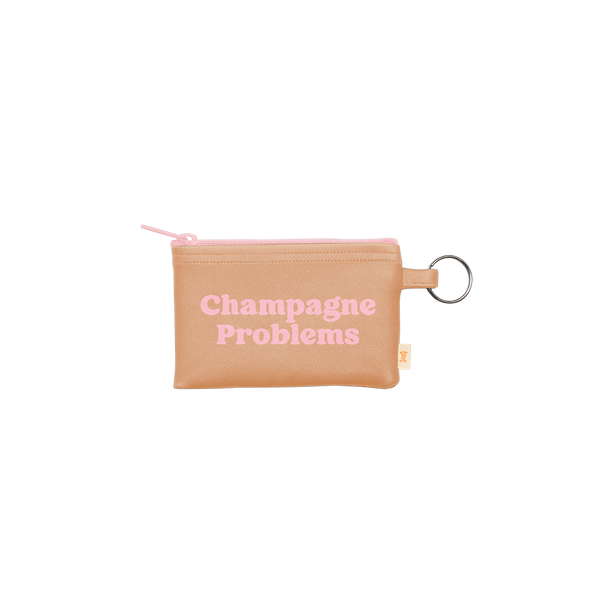 A small zippered pouch with an attached gold key ring. The main color of the pouch is tan and the saying "Champagne problems" is written in pink in the center.