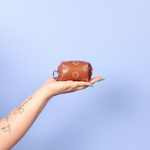Blue background and a small brown, colorful smiley faces around tag a long key ring on a girls hand
