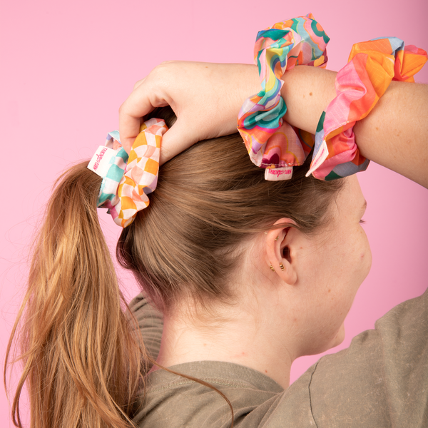A set of 3 super cute scrunchies made out of life proof/rip proof materials in funky trippy patterns in an array of colors ranging from orange to lime green, purple, and blues.