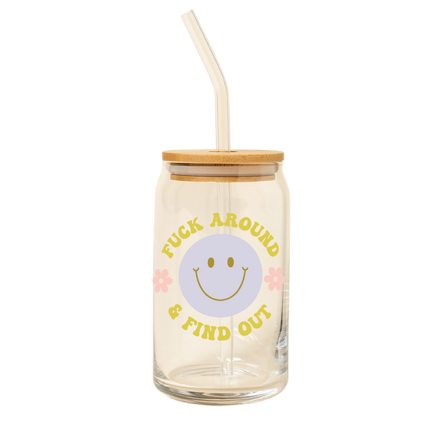 A clear can glass tumbler with lid and a clear straw. This clear can tumbler features a fun retro lavender smilie face in the center with the words " FUCK AROUND AND FIND OUT" written in citron color and two pink daisy's next to the smilie face.