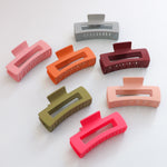 A collage featuring various colors of a rectangle claw clip.  Claw clips are a stylish way to hold sections of hair in place.