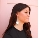A girl wearing a pair of silver, hanging mirror ball earrings. These earrings can be worn all day as they are very lightweight and go with any outfit!!
