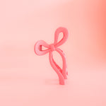A pink claw clip in the shape of a bow. This super fun accessory adds a pop of color to your day!!