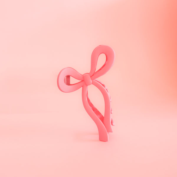 A pink claw clip in the shape of a bow. This super fun accessory adds a pop of color to your day!!