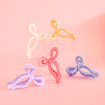 An assortment of bow shaped claw clips. The colors are lavender, light blue, yellow, cream and pink. These clips are a fun way to hold your hair in place!!