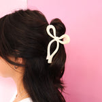 A girl with a cream colored bow shaped claw clip in her hair. The bow claw clip is super cute goes with all outfits!!