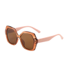 A pair of retro-inspired design, oversized hexagonal sunglasses with dark brown tinted lenses and translucent brown frames with blush colored arms. 