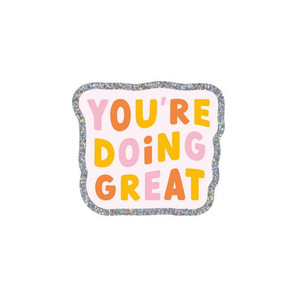 This sticker has a cheerful and encouraging message. "YOU'RE DOING GREAT" is written in all caps in alternating colors of pink, coral, and yellow. The sticker itself has a wavy, cloud-like outline with a silver glitter boarder and a pale pink background.