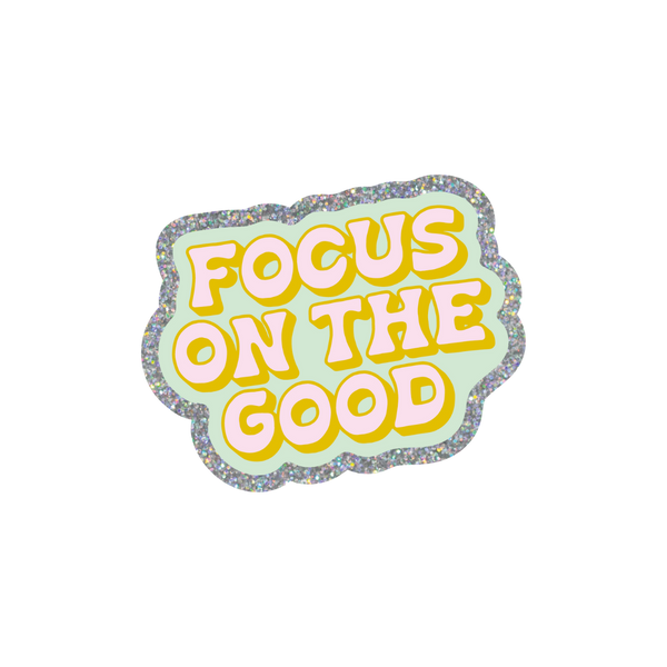 This sticker is scalloped shaped and sliver glitter boarder with a turquoise background. "FOCUS ON THE GOOD" is written in bold, retro style block letters. The text is written in light pink with a golden colored outline.