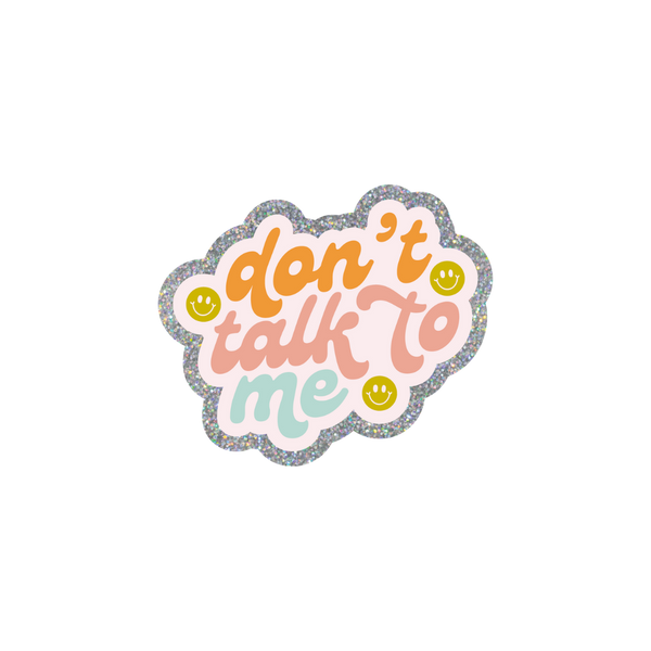 This sassy and playful sticker features a scalloped design with a silver glitter boarder. The text reads "don't talk to me" in orange, pink and light blue colors, written in cursive. There are three olive green smiley faces surrounding the text.