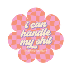 A daisy cut out sticker featuring a pink and orange checkered background with the saying "i can handle my shit" written in cream script writing with a lavender outline.