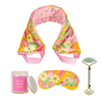 A cute funky set of our self care items that includes a candle with a pink label and a jar lid, a jade green stone face roller with a saying on it, a weighted eye mask in a floral funky daisy print, and a weighted neck wrap in the same print that would be perfect as a gift or for personal self care.