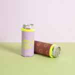 Two slim can coolers (koozies) designed to fit tall beverages. One is lavender with neon yellow stitching and text that reads "don't talk to me." The other is a rust brown color with a pattern of neon smiley faces, also edged with neon yellow. Both are holding silver cans and are set against a pastel pink and green background.
