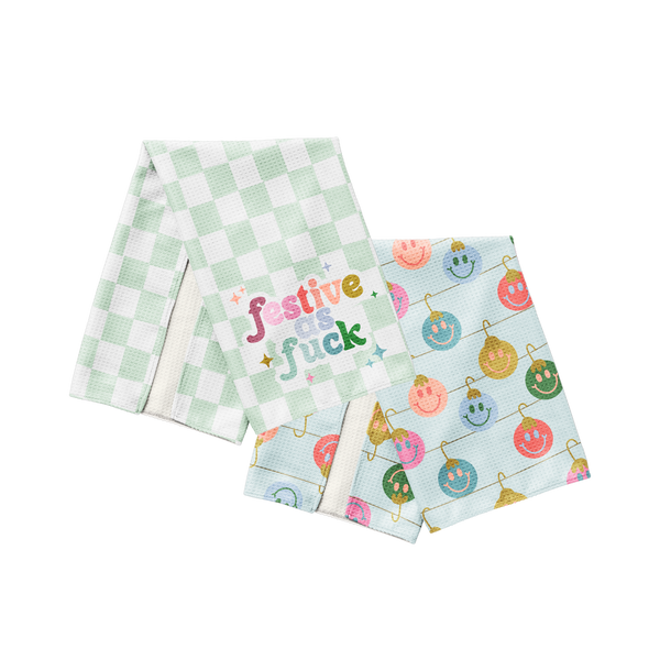 Bring the holiday cheer with a side of attitude. This tea towel duo includes a minty fresh checkered towel boldly stating "festive as fck"* and a second towel covered in pastel smiley-faced ornaments that scream merry and bright (with a wink). Made for holiday hosts who serve sass with their sugar cookies, these towels are both functional and fabulous—perfect for decking your kitchen with zero chill.