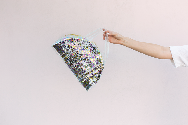 Lady holding confetti Lil Miss Sunshine bag in front of pink wall. 