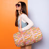 Young lady in sunglasses with a psychedelic flower patterned puffy duffle on her shoulder. 
