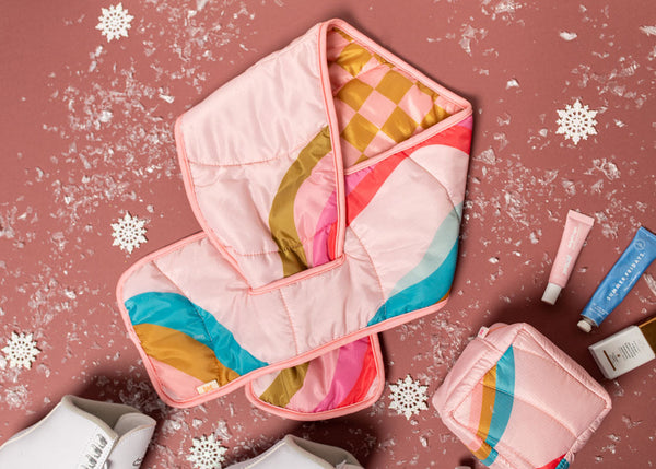 A warm, colorful puffy scarf with snowy confetti around it.