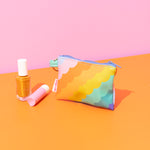 pastel rainbow scalloped stripe graphic on a small pouch with a key ring and blue zipper along with misc items.