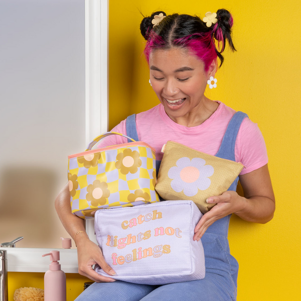 Mustard yellow background with a girl holding two medium waffle pouches with a cool funky daisy soulmate. 