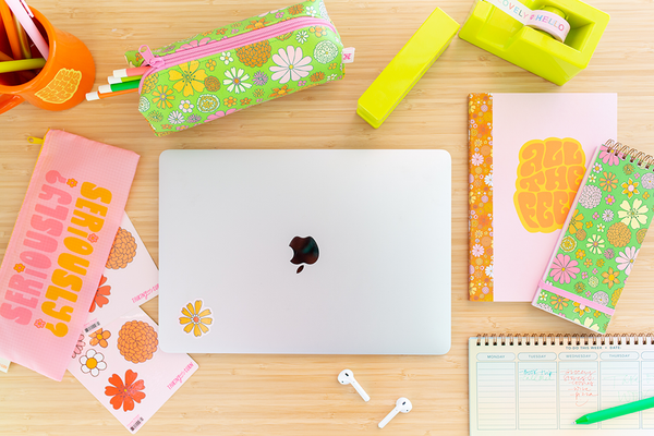 desk set up with floral pencil pouch, notebooks, stickers, surrounding computer