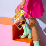 Girl walking up stairs with a psychedelic flower dollface clear vinyl  pouch carrying sunglasses.  