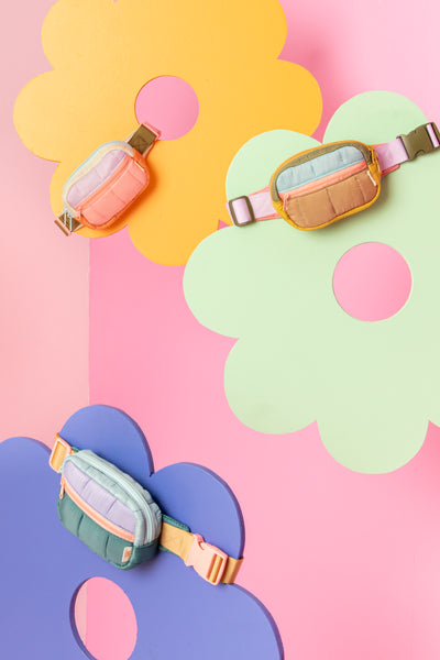 All small multi-color puffy bag on colorful daisy displays. Pink background.
