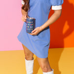 Girl in a blue dress and white knee high boots holding Talking Out Of Turn's "What A Time To Be Alive" 12.oz Tumbler.