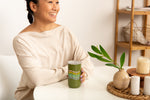 Girl in white holding a green tumbler that reads "what day is it?" in rainbow colors