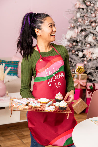 Red apron that says "Fa La fucking La" with white text.