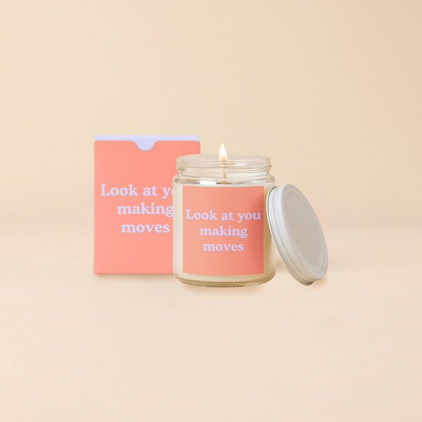 A 8 oz. candle jar with lid, with an orange decal on it "Look at you making moves" printed on.