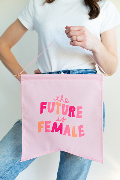 Girl holding up "the future is female" large wallflower. 