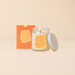 Glass jar candle reading "ALL THE FEELS" in orange bubble lettering. Box packaging with same text as candle. 