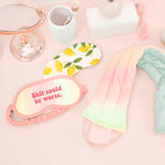 a pastel neck wrap, lemons weighted eye mask, and a pastel sleep mask on a pink background