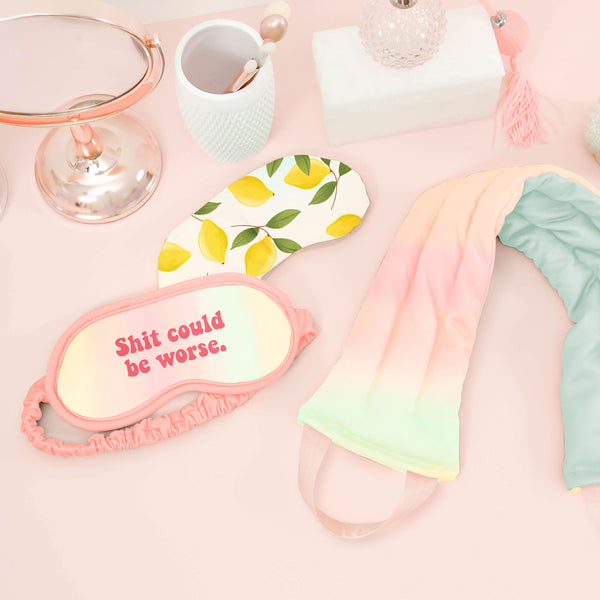 a pastel neck wrap, lemons weighted eye mask, and a pastel sleep mask on a pink background