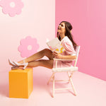 Girl in folding chair laughing with a floral print notebook. 