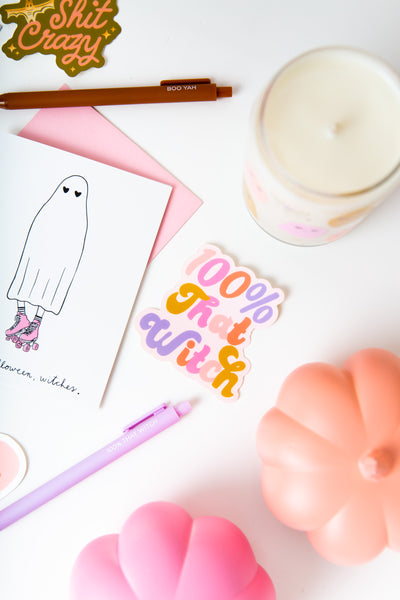 white sticker with multi color ( pink, light pink, coral pink, lavender purple, mustard yellow gold) lettering saying "100% that witch".