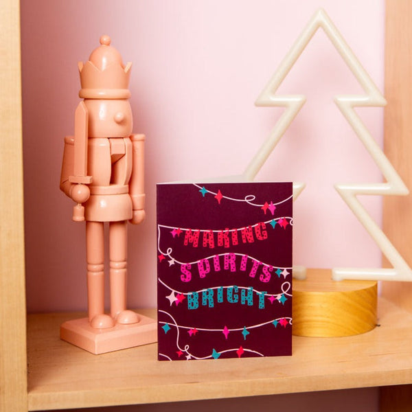 Dark red "MAKING SPIRITS BRIGHT" card next to a nutcracker