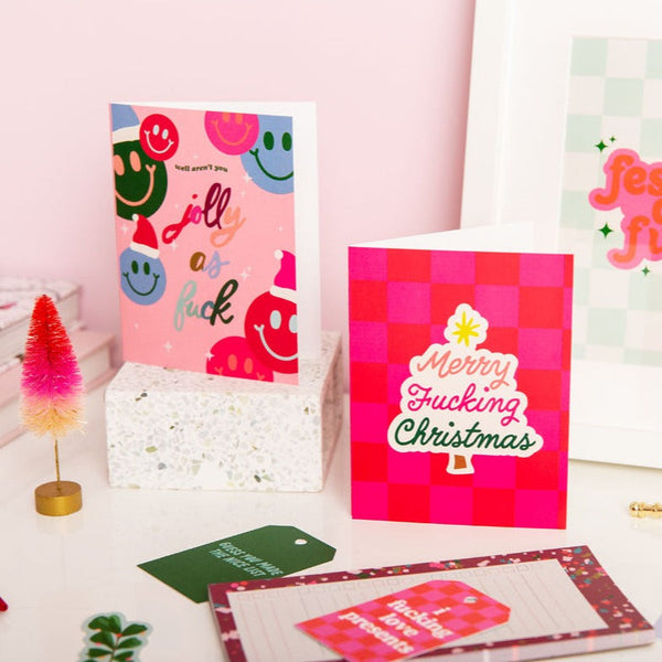 Two holiday cards standing on their own. Colorful "Jolly as fuck" and hot pink/red "Merry Fucking Christmas"