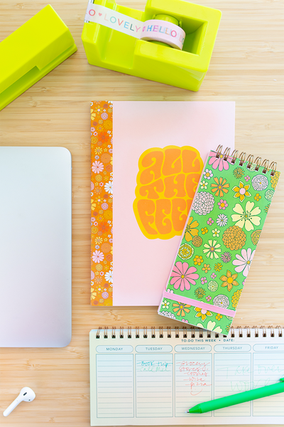 desk set up with different notebooks, weekly task pad, lime green stapler and tape dispenser