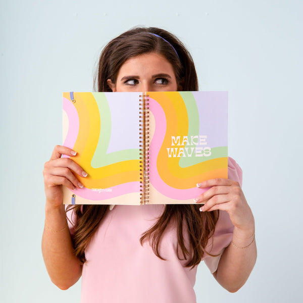 Model holding the Making Waves notebook and a powder background.