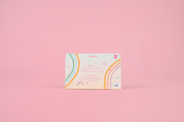 a pink weighted eye mask with assorted color tiny hearts in toots colorful packaging on a pink background.