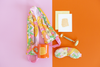 collection of floral printed self care items with a stone roller and an orange mug and letterpress card with the saying 