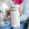 Lady holding a white tumbler with a colorful 