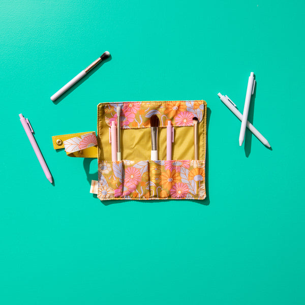 Open gathering flowers small tootsie roll with misc items inside on a teal color background. 