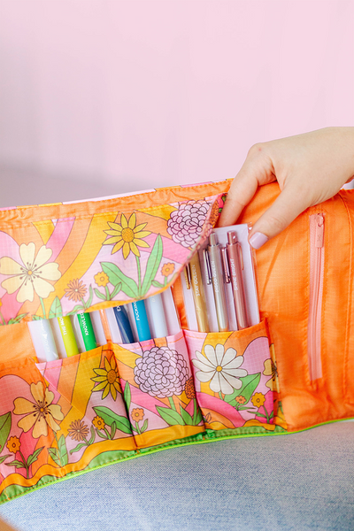Fingers grabbing jotter pens from the Inside of large TOOTsie roll with floral and swirl pattern in pink and orange