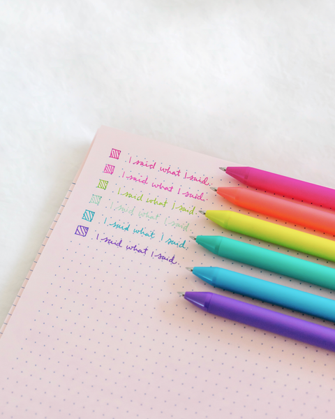 Colorful pens from the "unleash the fury" jotter set laying on a bullet journal  with writing in each pen color next to them. 