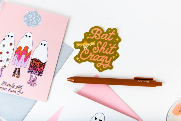 Halloween card, pen, and sticker in olive green and yellow that reads "Bat Shit Crazy"