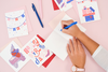 A collection of white birthday cards. A woman is writing in an open card. 